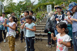 御巣鷹の尾根の昇魂之碑の前でシャボン玉を飛ばす子どもたちの写真