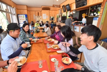 山の鼻小屋で食事しながら談笑するハイカーの画像