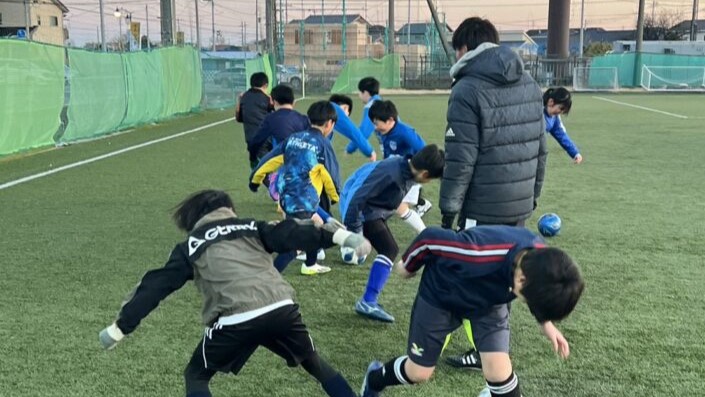子どもにサッカーを教える写真
